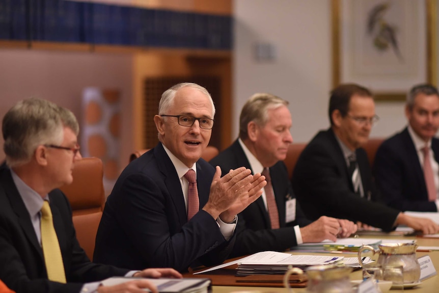 Malcolm Turnbull speaks during a COAG meeting, sits with 5 other men in a boardroom.