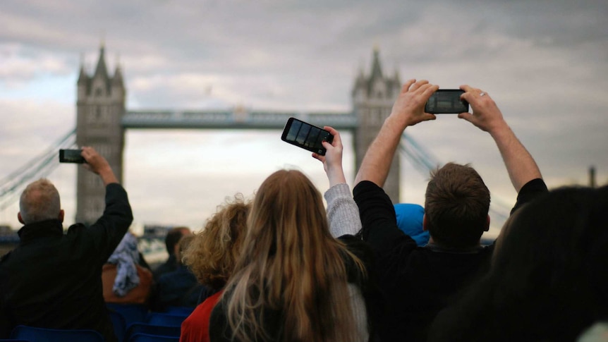 People crane to take photos of London Bridge.