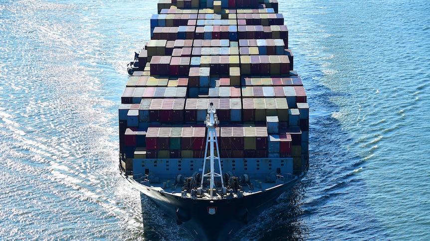 A cargo ship full of multi-coloured containers sails towards the camera.