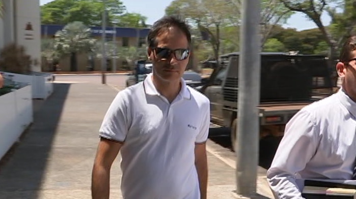 Alexandros Deligiannis, flanked by a man in a suite, walks out of court in the Darwin CBD.