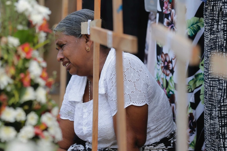 A Sri Lankan woman cries sitting next to the grave of her family member who died in Easter Sunday attacks.
