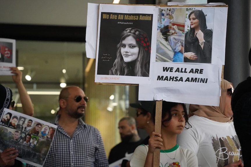 Close up of signs that say 'we are all Mahsa Amini' 