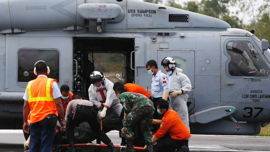 The body of an AirAsia passenger is unloaded from a US navy helicopter