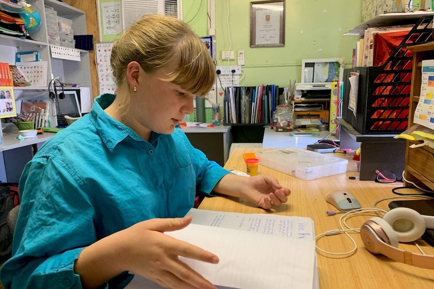 A student looks at her class notes working in a home office.