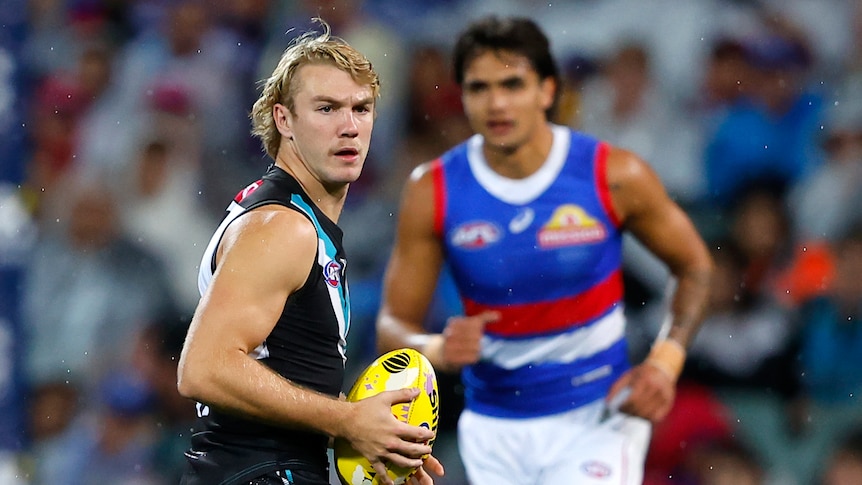 A Port Adelaide AFL player holds the ball unopposed against the Western Bulldogs.
