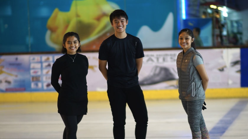Nurul Ayinie Sulaeman, Calvin Pratama and Savika Refa Zahira smile while they stand on the ice.