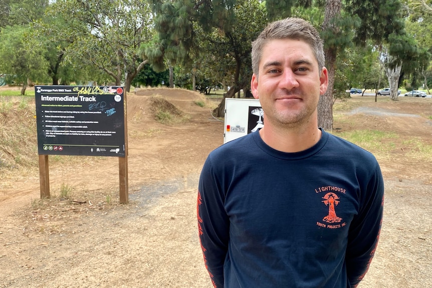 A man wearing a blue shirt standing on a dirt track