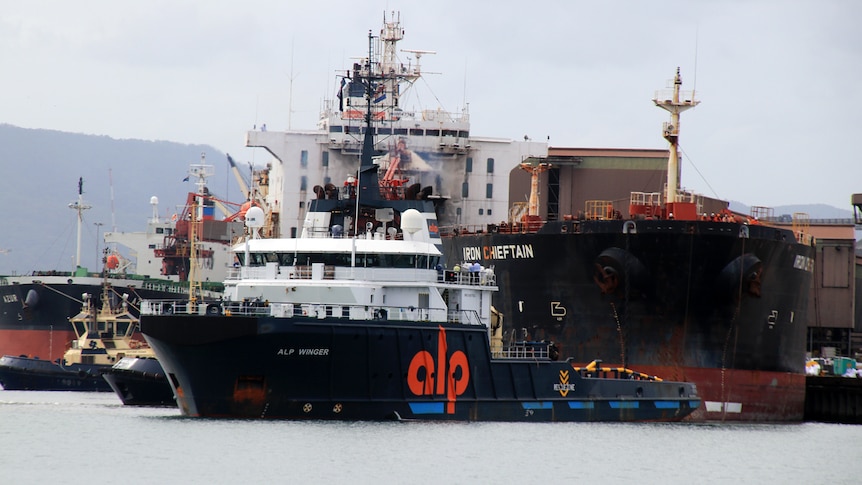 A bulk carrier gets towed out of Port Kembla by another vessel