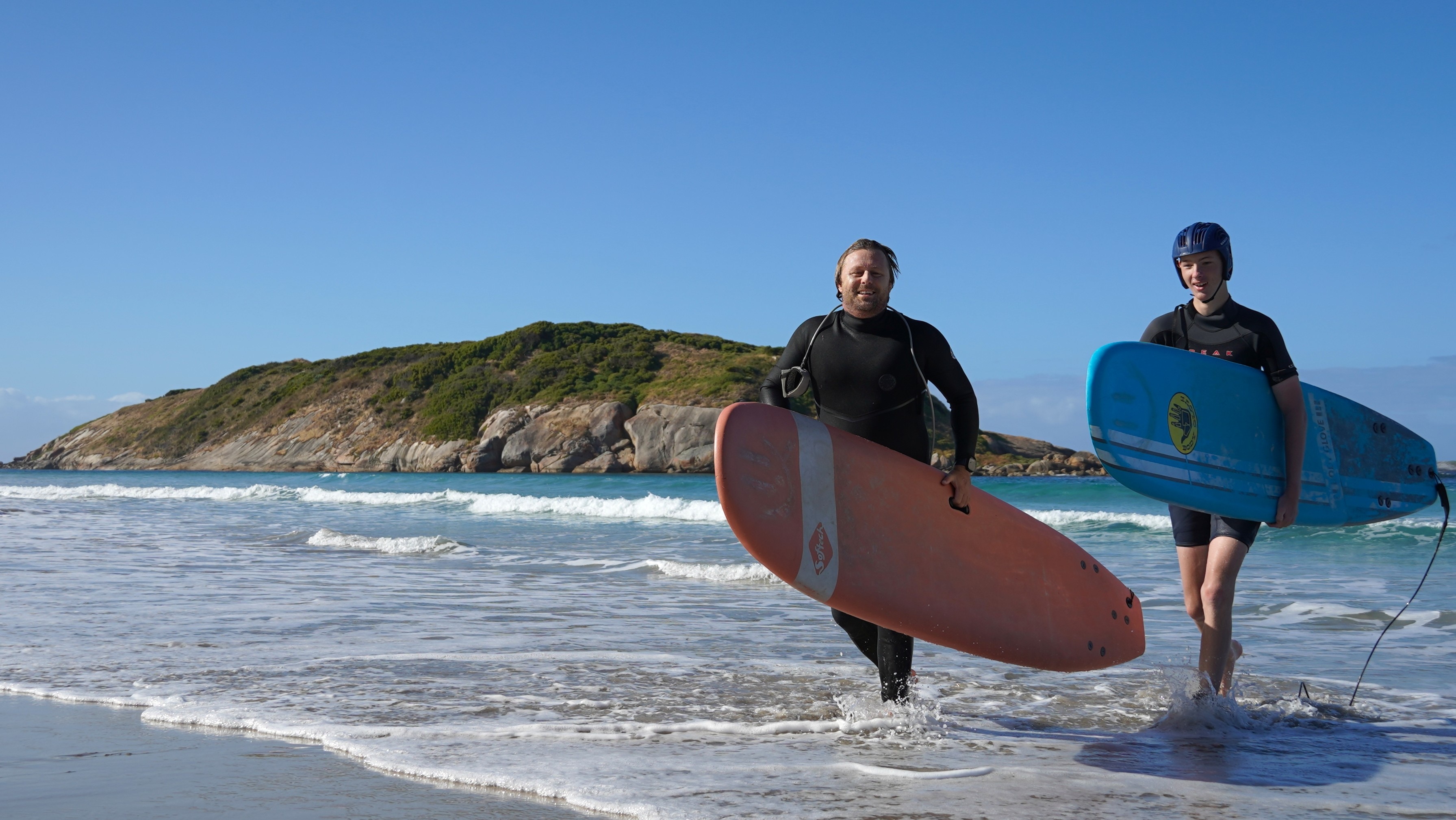 Sascha and Max carry their boards out of the water. 