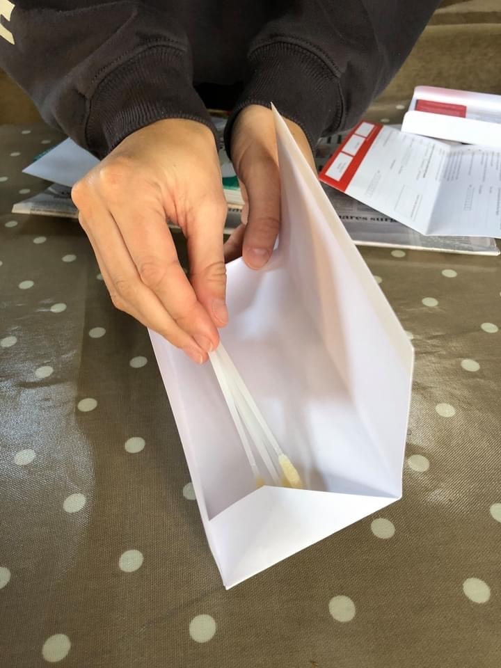 Swabs being placed into an envelope.