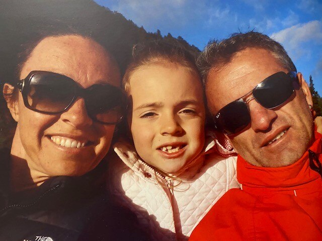 A photograph of a couple and their child smiling happily.