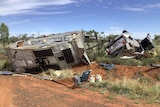 A, crashed, upside down 4wd and caravan on it's side of a red dirt highway. 