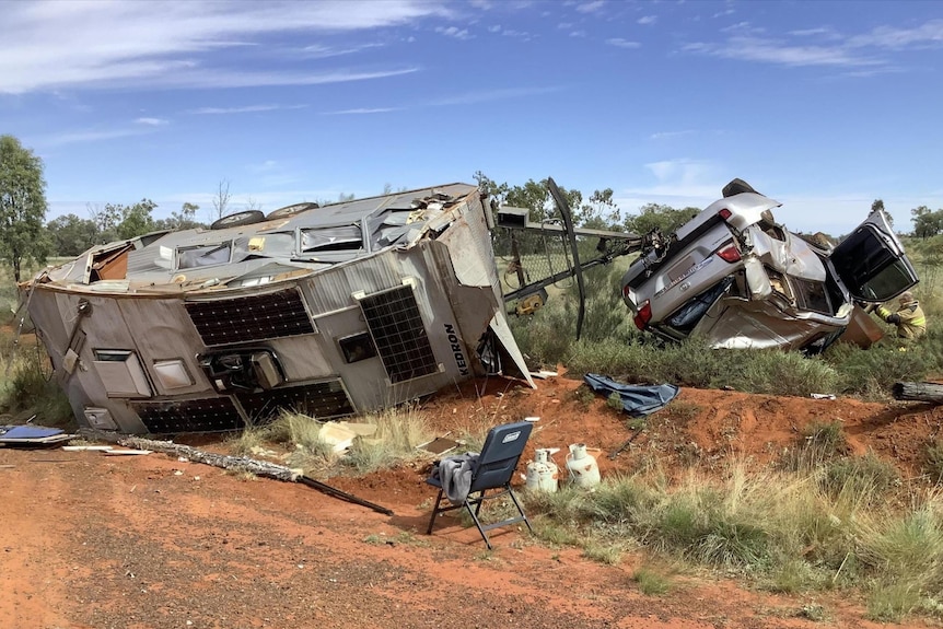 A, crashed, upside down 4wd and caravan on it's side of a red dirt highway. 