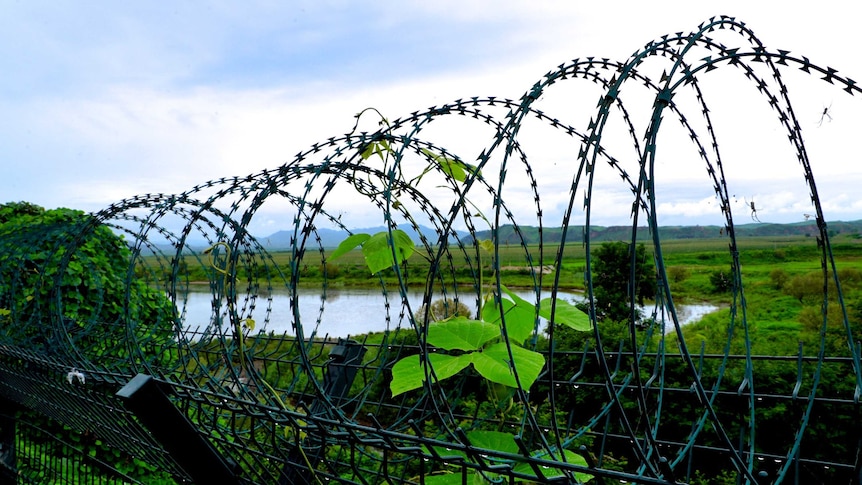 Looking into North Korea from Chinese side of the border through wire fencing.