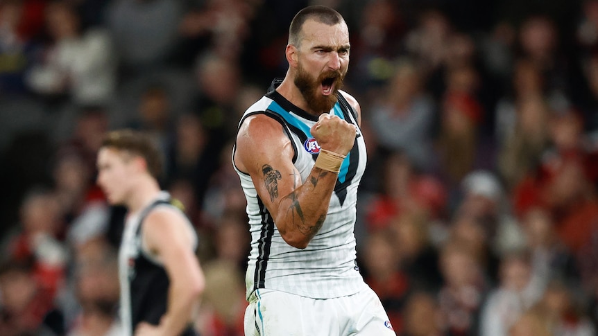 A Port Adelaide AFL player pumps his right fist as he celebrates a goal against St Kilda.
