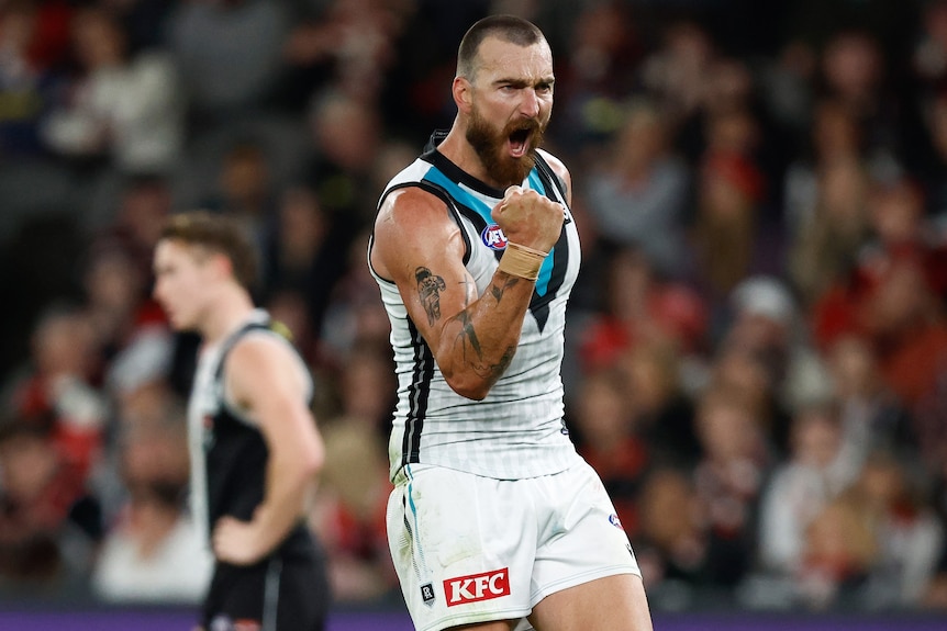 A Port Adelaide AFL player pumps his right fist as he celebrates a goal against St Kilda.