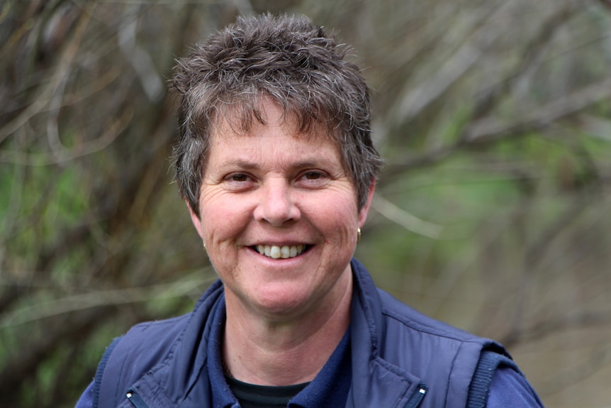 A lady in a blue vest smiling