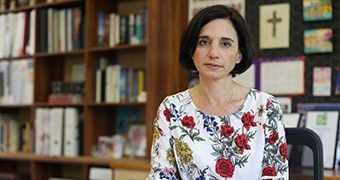 A school principal sits at her desk looking serious.