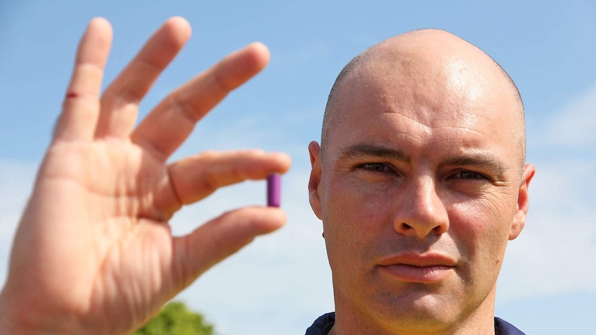 Heat stress consultant Matt Brearley stands with an ingestible pill that tracks core body temperature.