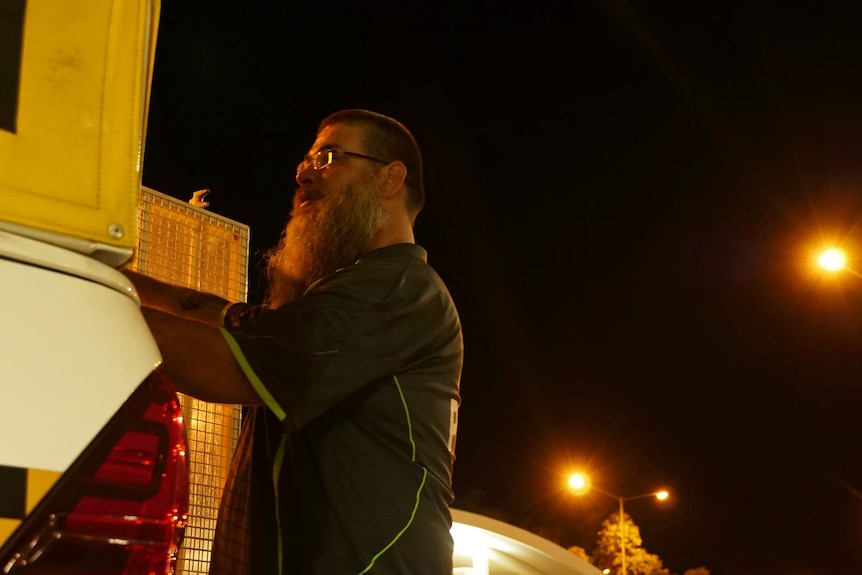 A photo of a man closing the gate on a night patrol van.