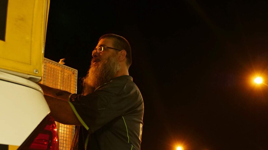 A photo of a man closing the gate on a night patrol van.