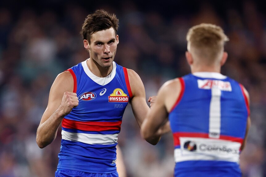 A Western Bulldogs player clenches both fists in celebration as he looks to a teammate after a goal.