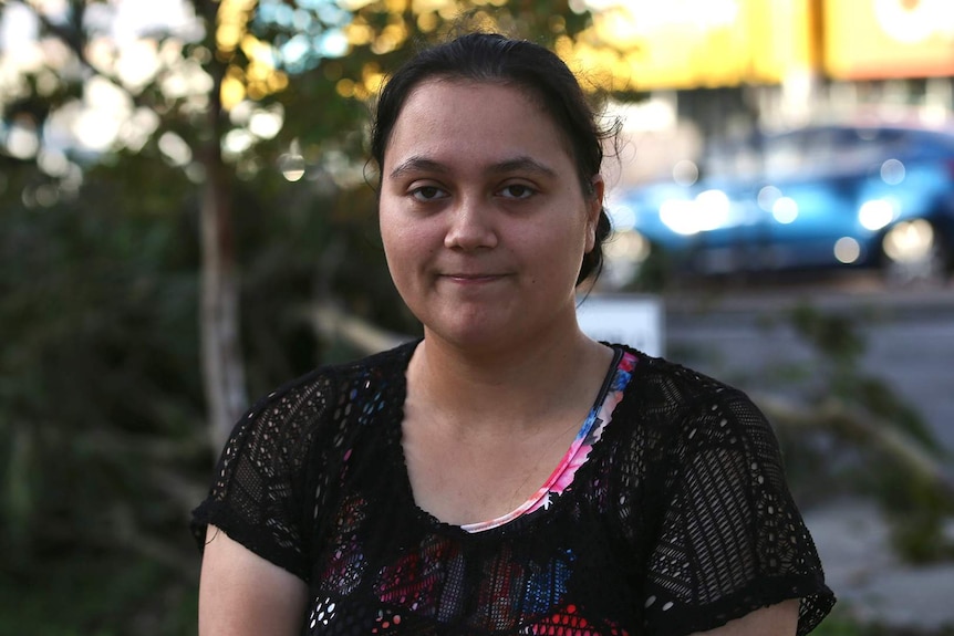 A head and shoulders shot of a young woman posing for a photo outdoors looking glum.