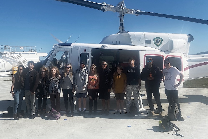 Members of Tasmania's Aboriginal community pose next to a helicopter.