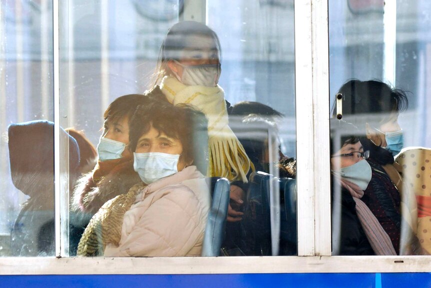 Women on a train with face masks behind glass on a trolley bus.