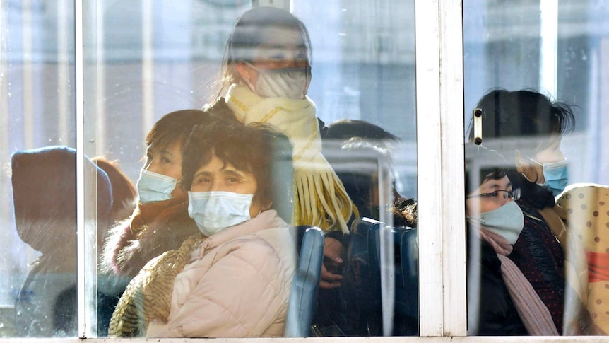 Women on a train with face masks behind glass on a trolley bus.