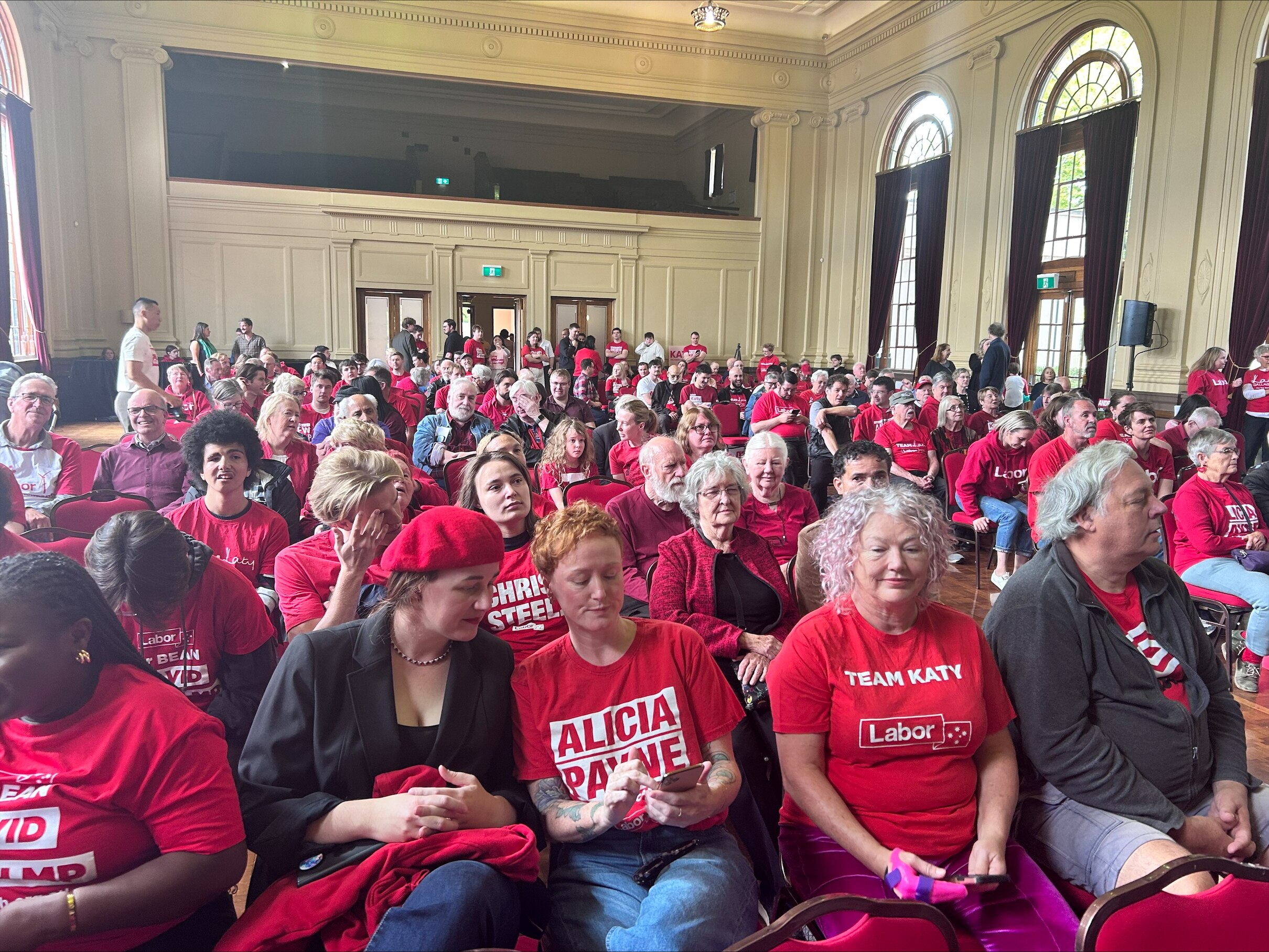 A hall full of people who wear red labor shirts. 
