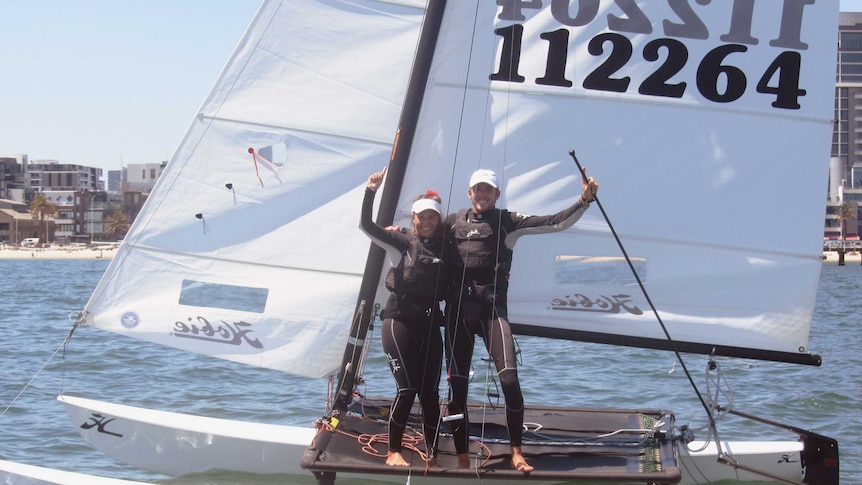 The two sailors aboard a yacht on the water.