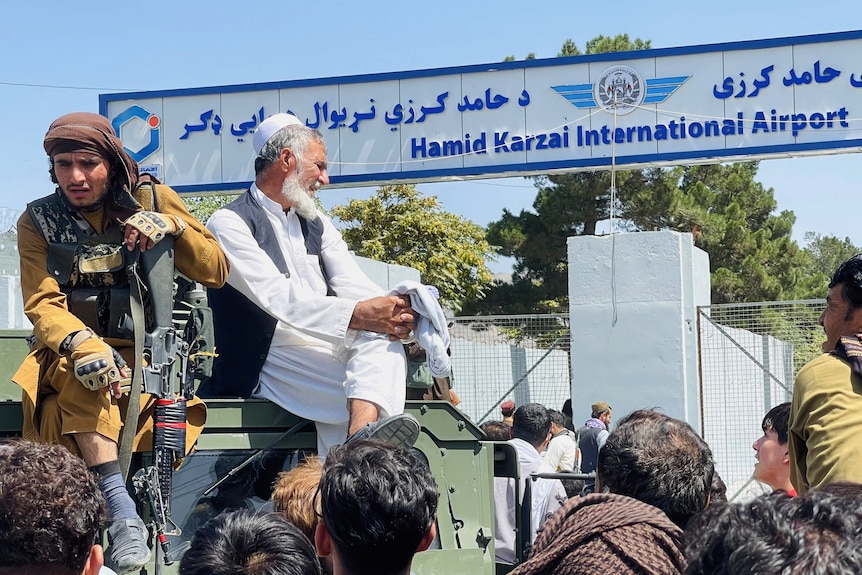 Due uomini seduti su un furgone blindato davanti all'aeroporto di Hamid Karzai