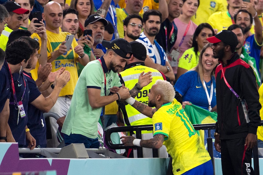 Neymar embraces injured Brazil teammate Alex Telles in the stands after a goal against South Korea at the Qatar FIFA World Cup.
