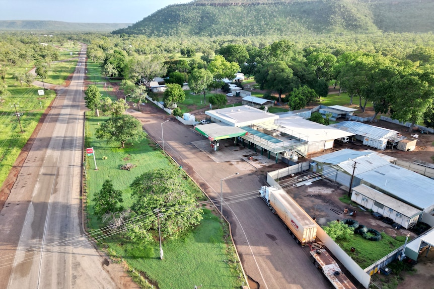 An aerial view of a main road running through a remote community, with a hotel and other commercial buildings on one side.