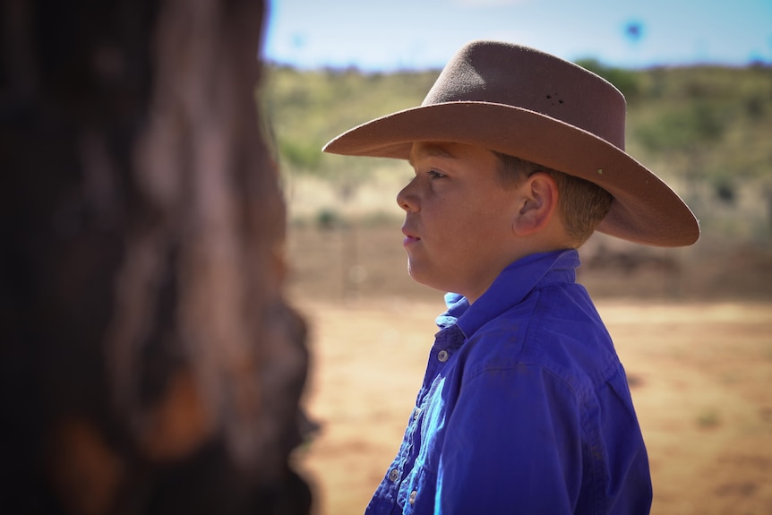 A side profile of a young boy wearing an Akubra.