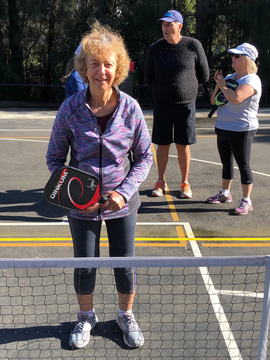 A woman stands on a court marked up for pickleball. 