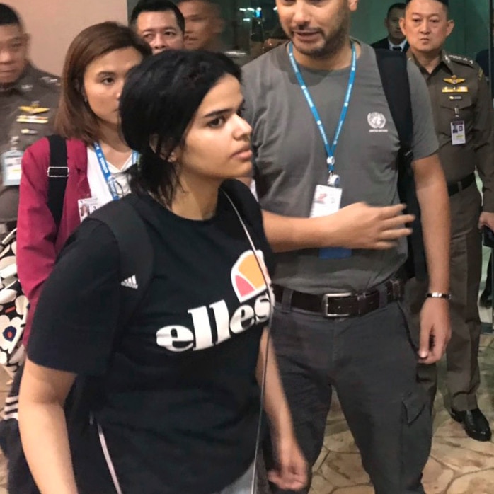 Rahaf Mohammed Alqunun walks past immigration police in Bangkok Airport
