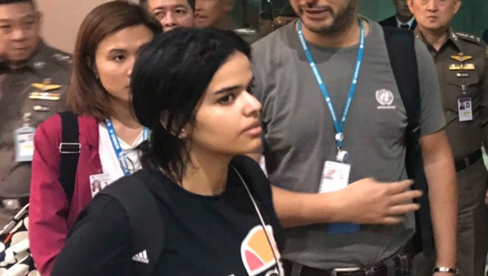 Rahaf Mohammed Alqunun walks past immigration police in Bangkok Airport