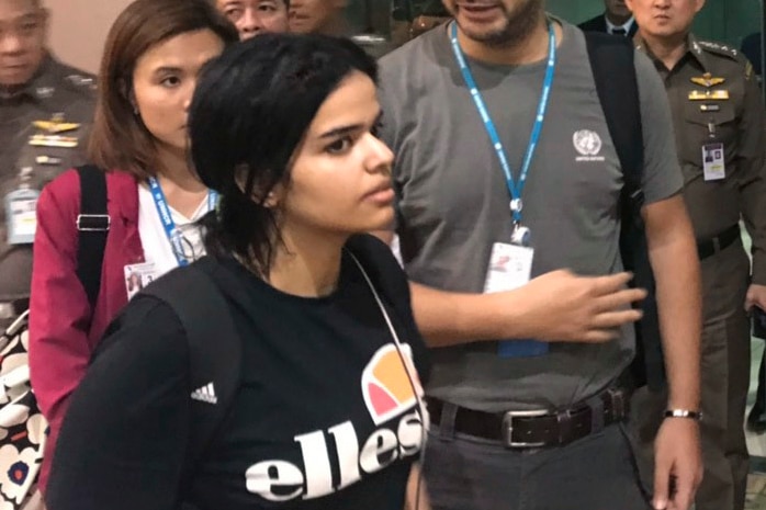 Rahaf Mohammed Alqunun walks past immigration police in Bangkok Airport
