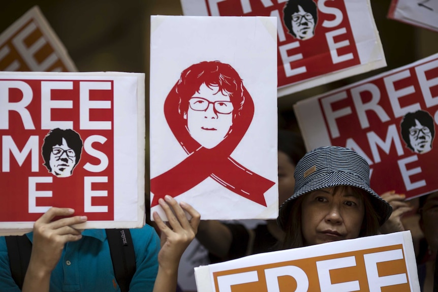 Protesters hold up placards to demand the release of Singaporean teenager Amos Yee outside the Singapore Consulate in Hong Kong, China July 5, 2015.