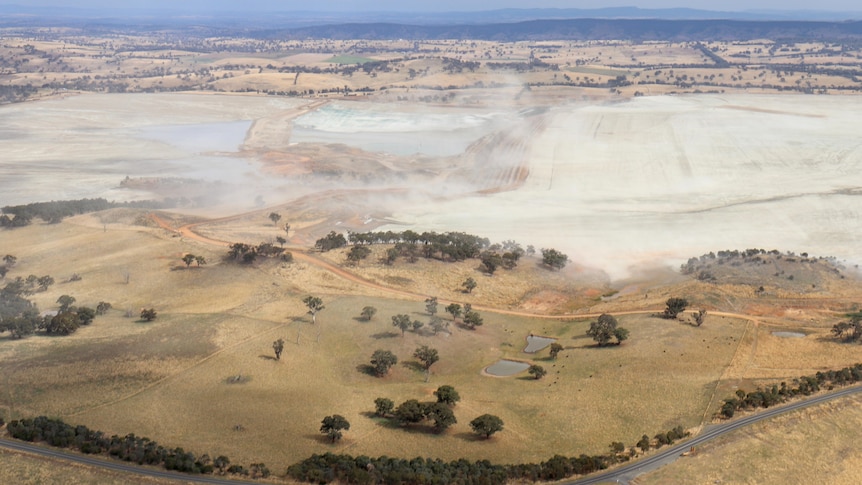 Aerial shot of mine with dust rising off surface