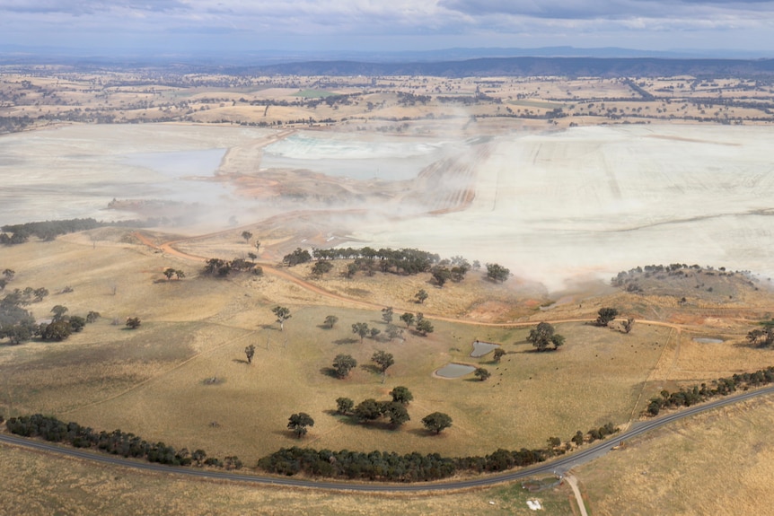 Aerial shot of mine with dust rising off surface