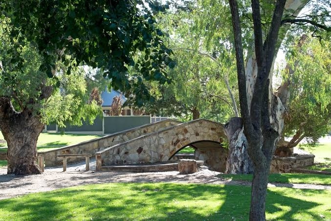 A stone bridge in a park with trees