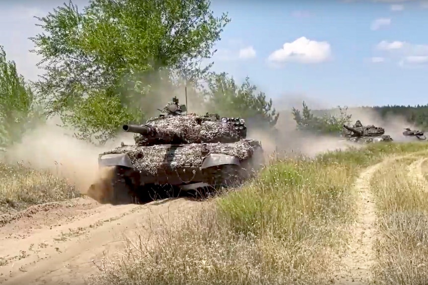Russian tanks drive down a dirt road on a mission at an undisclosed location in Ukraine.
