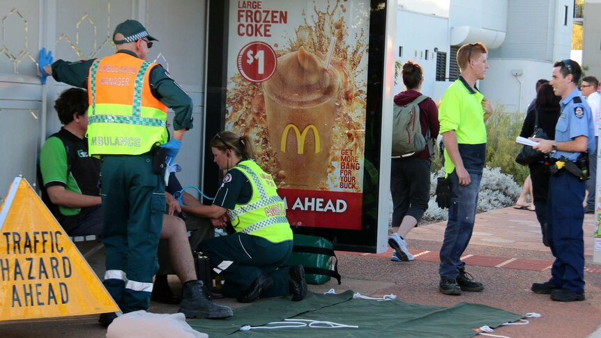 Emergency services workers treat an injured passenger at a bus stop.