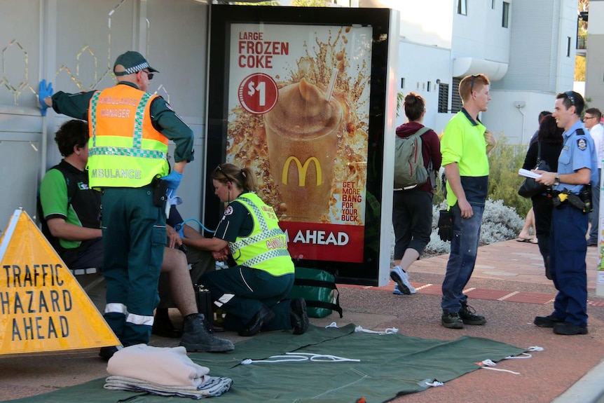 Emergency services workers treat an injured passenger at a bus stop.