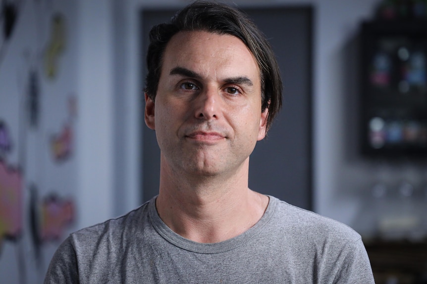 A man wearing a grey shirt staring straight at the camera