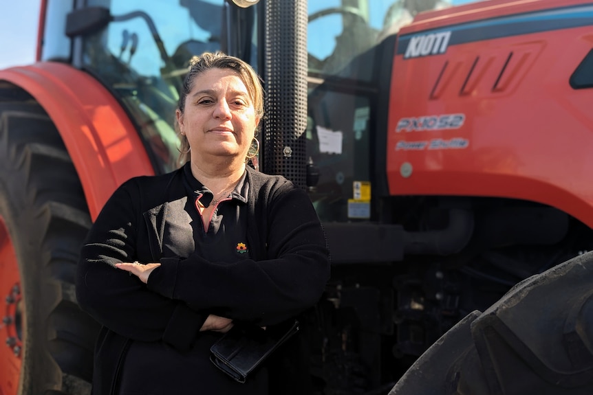A middle-aged woman standing in front of a tractor.
