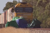 A freight train crashed into a car covered in a tarpauline